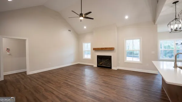 an empty room with wooden floor fireplace and windows