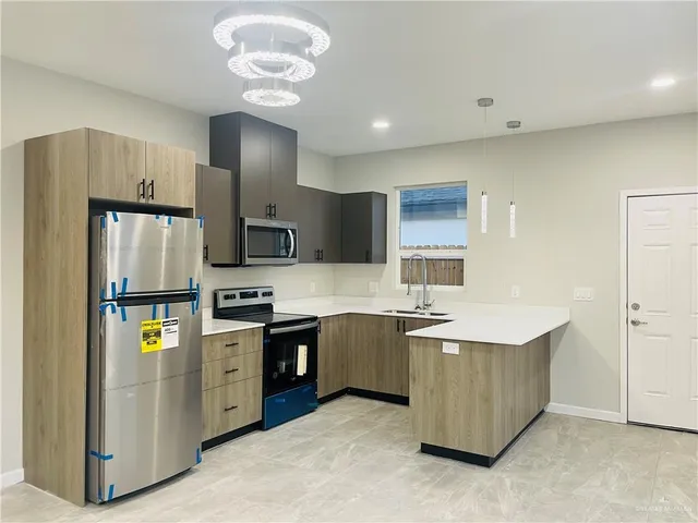 a kitchen with stainless steel appliances granite countertop a refrigerator a stove top oven a sink and dishwasher