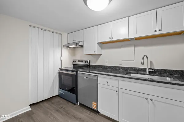 a kitchen with granite countertop white cabinets and a sink