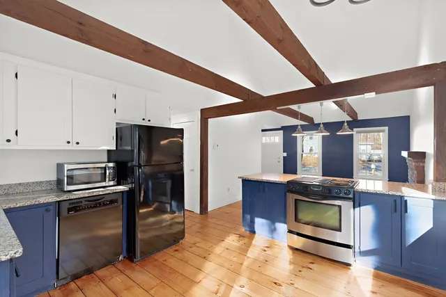 a kitchen with stainless steel appliances kitchen island granite countertop a stove refrigerator and cabinets