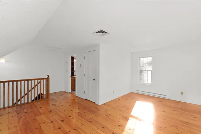 a view of a bedroom with wooden floor and window