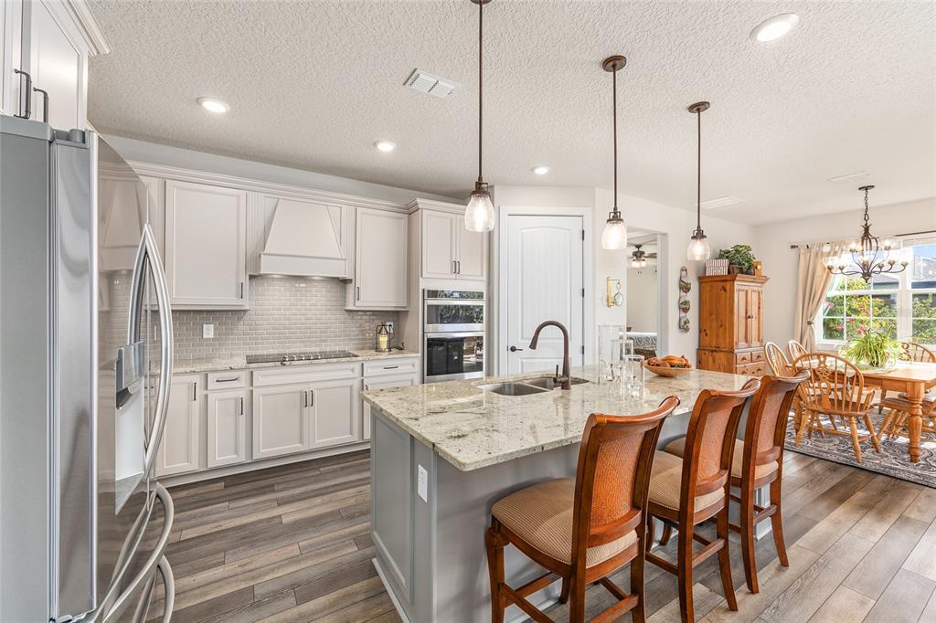 8986 Southwest 58th Street Road Ocala, FL 34481 - Photo 16 of 53 a kitchen with stainless steel appliances kitchen island granite countertop a dining table chairs and white cabinets