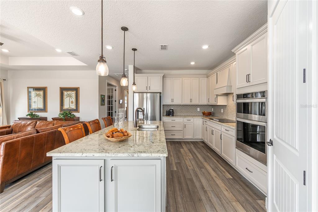 8986 Southwest 58th Street Road Ocala, FL 34481 - Photo 19 of 53 a kitchen with stainless steel appliances a stove a sink a refrigerator white cabinets and couches with wooden floor