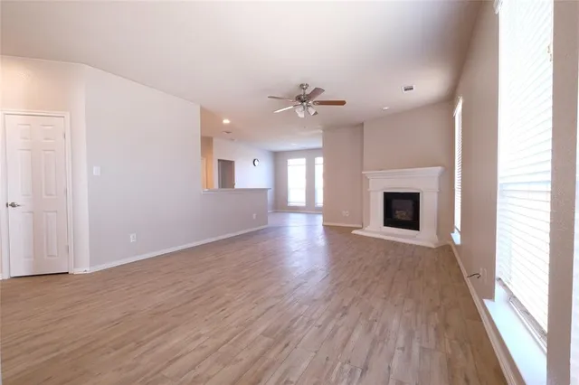 an empty room with wooden floor fireplace and windows