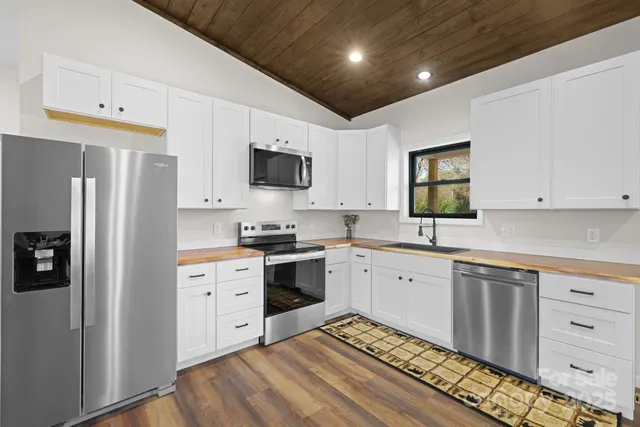 a large white kitchen with stainless steel appliances granite countertop a stove a sink and a refrigerator