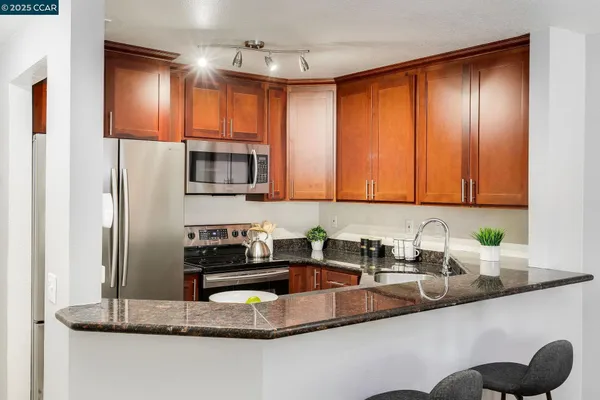 a kitchen with stainless steel appliances granite countertop a refrigerator a sink a stove a microwave and island with wooden floor