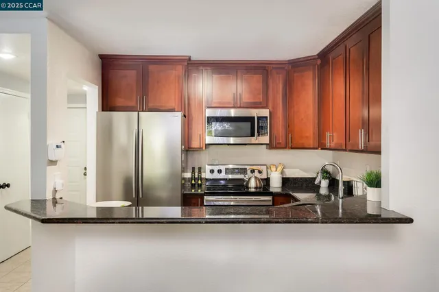 a kitchen with stainless steel appliances granite countertop a refrigerator and a sink