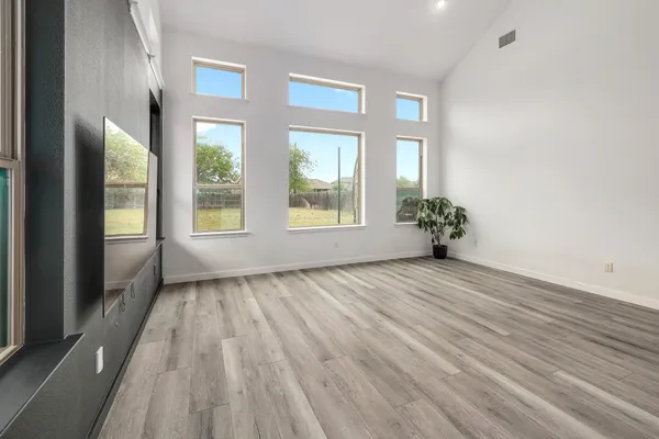 a view of an empty room with a window and wooden floor