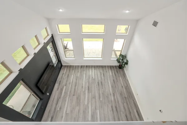 a view of empty room with wooden floor and fan