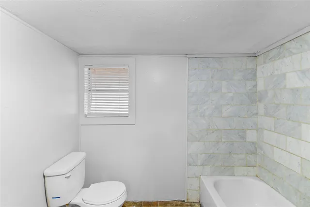 a white toilet sitting next to a bath tub