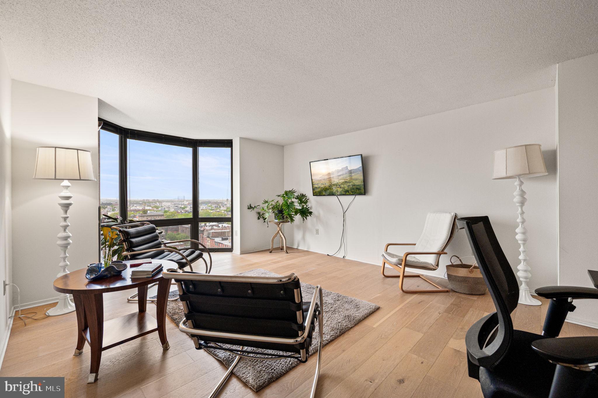 2018 Walnut Street, Unit 15M Philadelphia, PA 19103 - Photo 2 of 31 a living room with furniture a flat screen tv and a floor to ceiling window