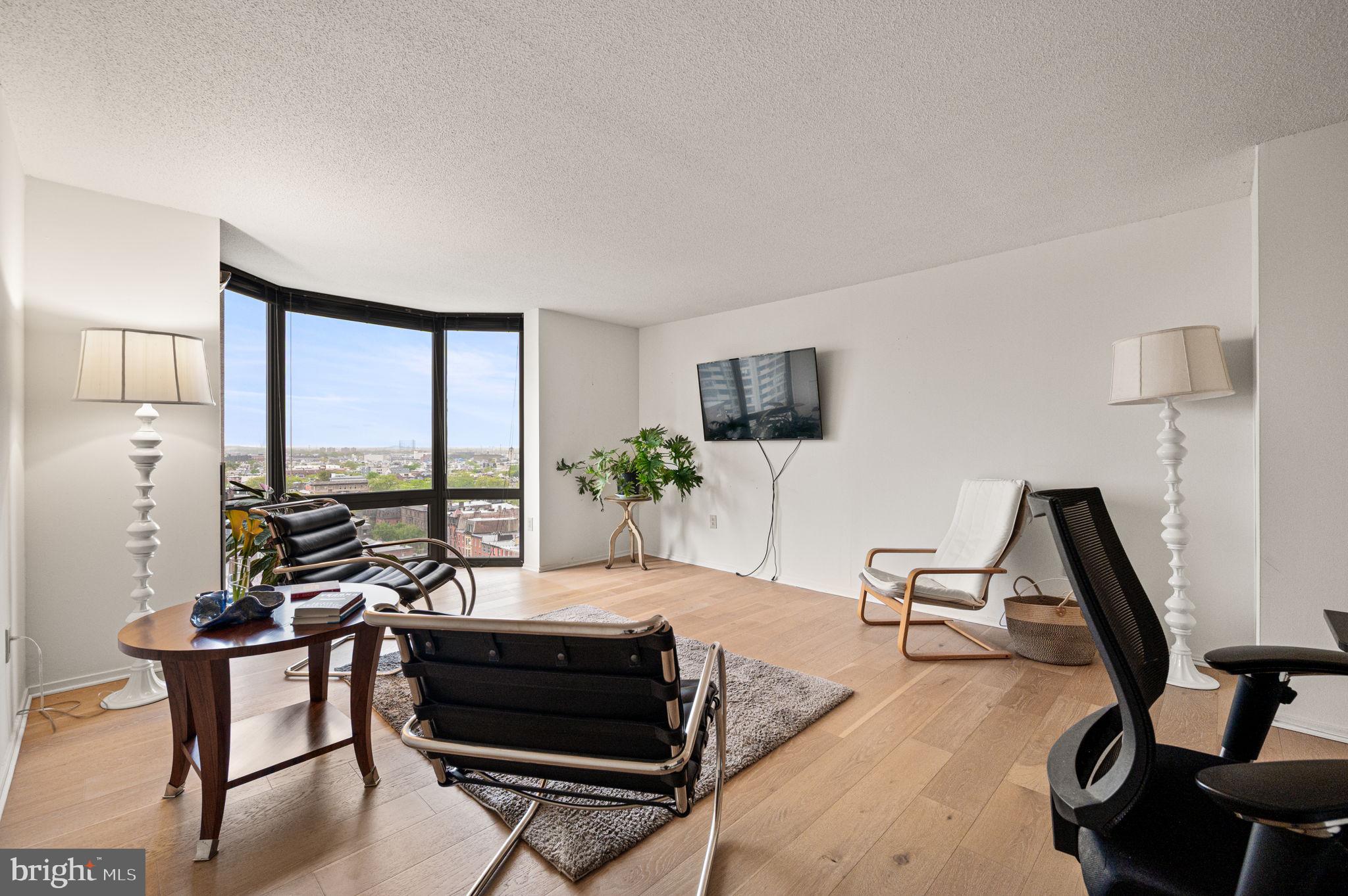 2018 Walnut Street, Unit 15M Philadelphia, PA 19103 - Photo 4 of 31 a living room with furniture a flat screen tv and a floor to ceiling window