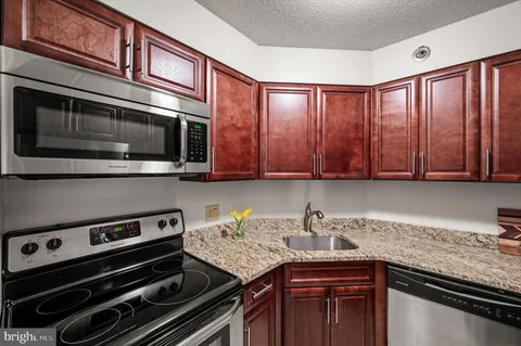 a kitchen with granite countertop a stove cabinets and microwave