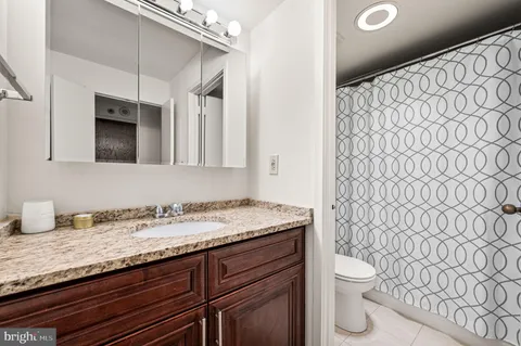a bathroom with a granite countertop sink and a toilet