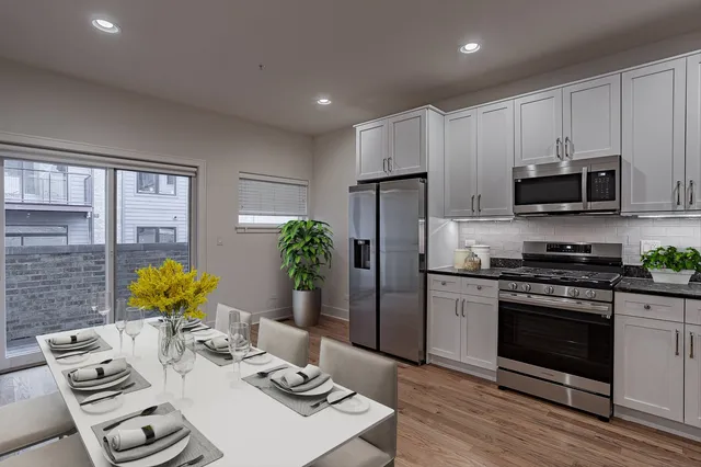 a kitchen with stainless steel appliances a stove a refrigerator a sink a dining table and chairs