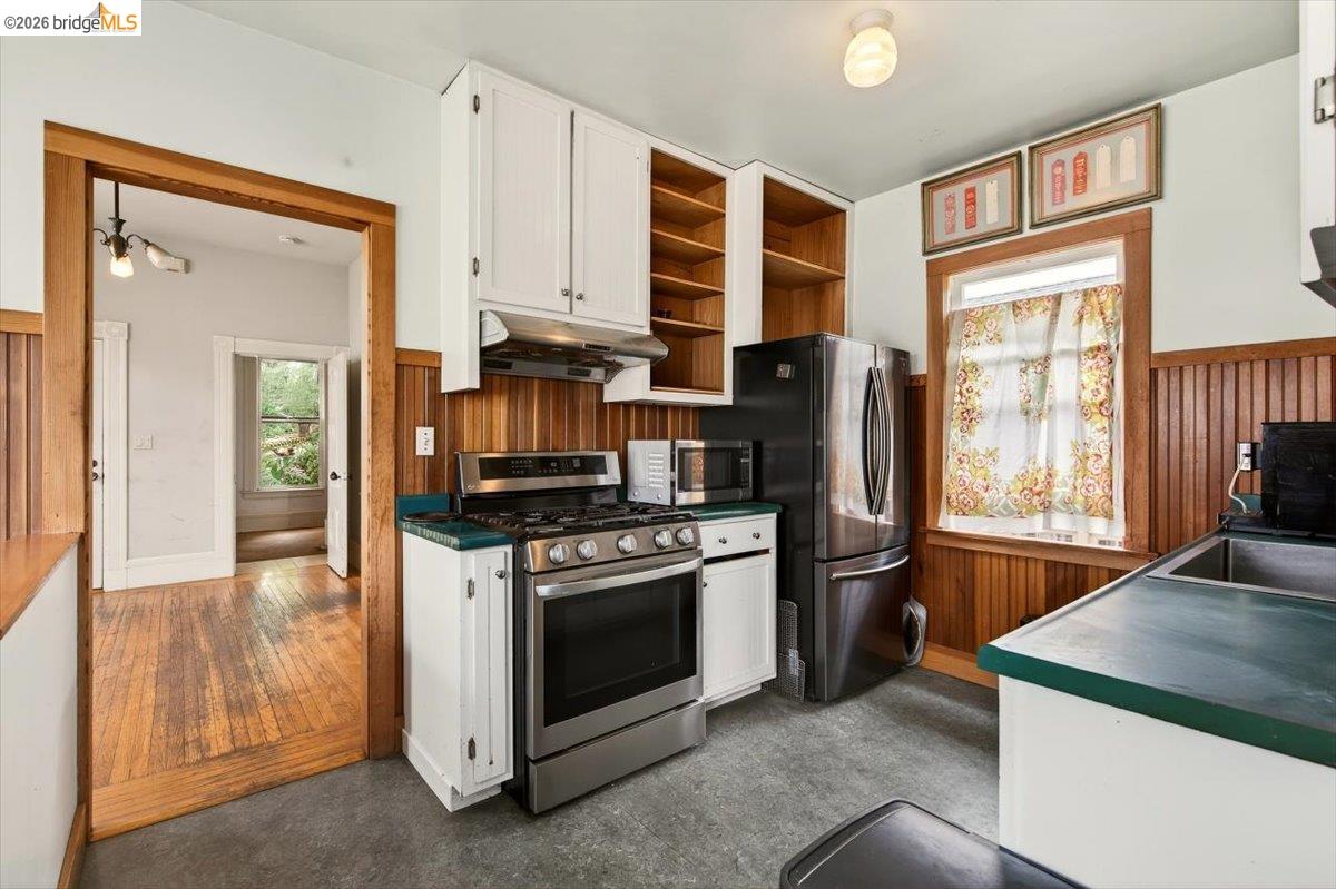 1013 Addison Street Berkeley, CA 94710 - Photo 23 of 57 Kitchen with white cabinetry, stainless steel appliances, dark countertops, wainscoting, and wooden walls