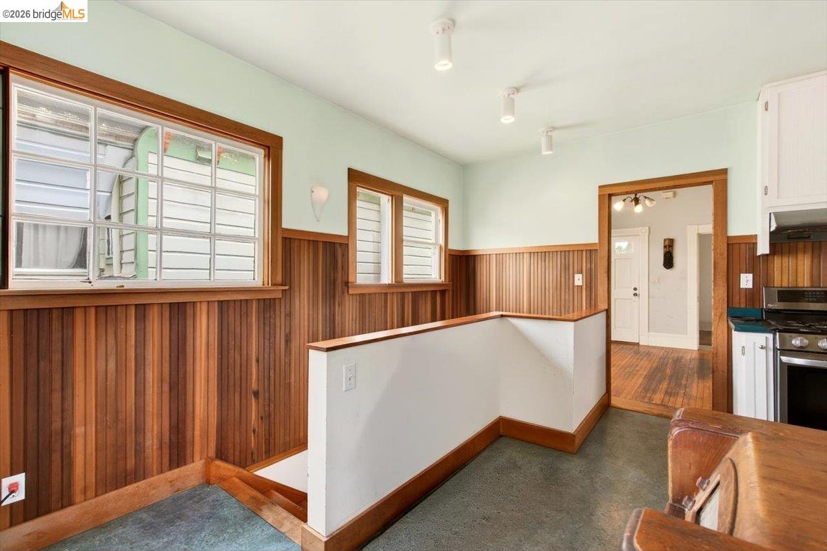 1013 Addison Street Berkeley, CA 94710 - Photo 25 of 57 Kitchen with wainscoting, wood walls, stainless steel gas range oven, white cabinetry, and dark colored carpet