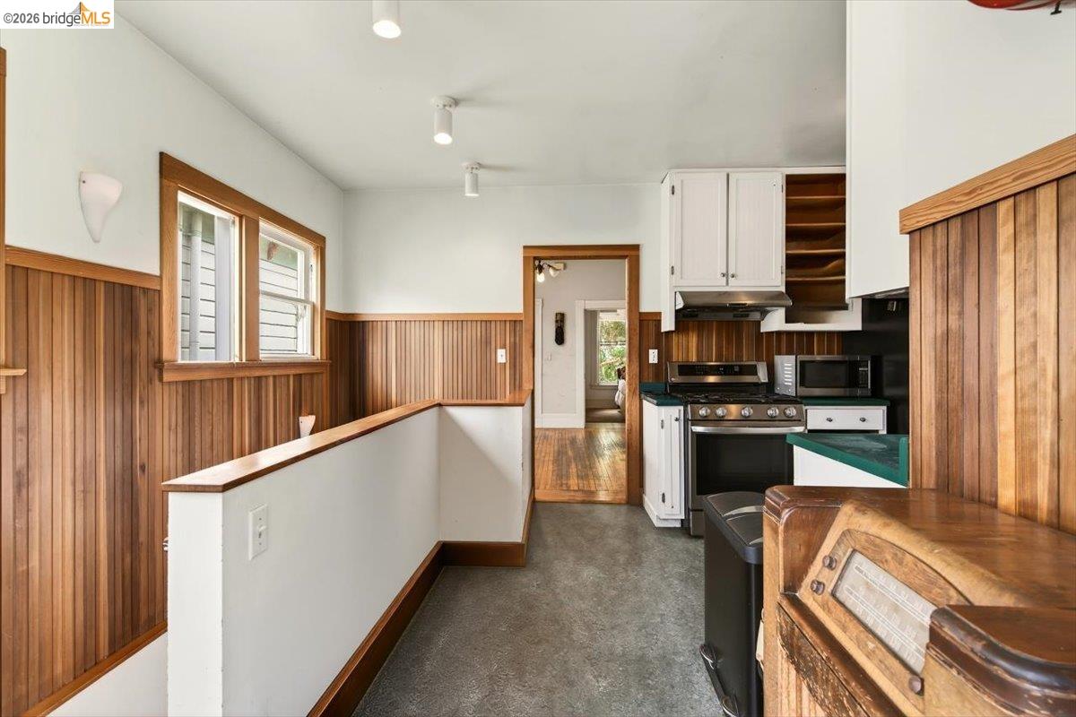 1013 Addison Street Berkeley, CA 94710 - Photo 26 of 57 Kitchen featuring wood walls, white cabinetry, a wainscoted wall, stainless steel appliances, and dark countertops