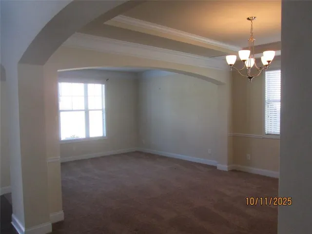 en empty room with windows and chandelier