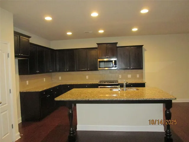 a kitchen with stainless steel appliances granite countertop a sink a stove and a microwave