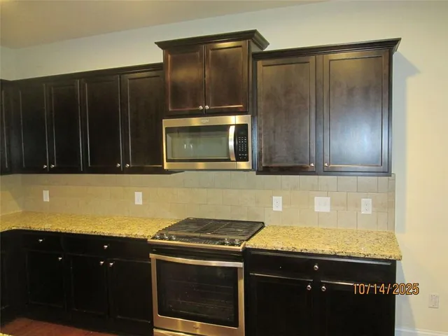 a kitchen with granite countertop wooden cabinets and a stove top oven
