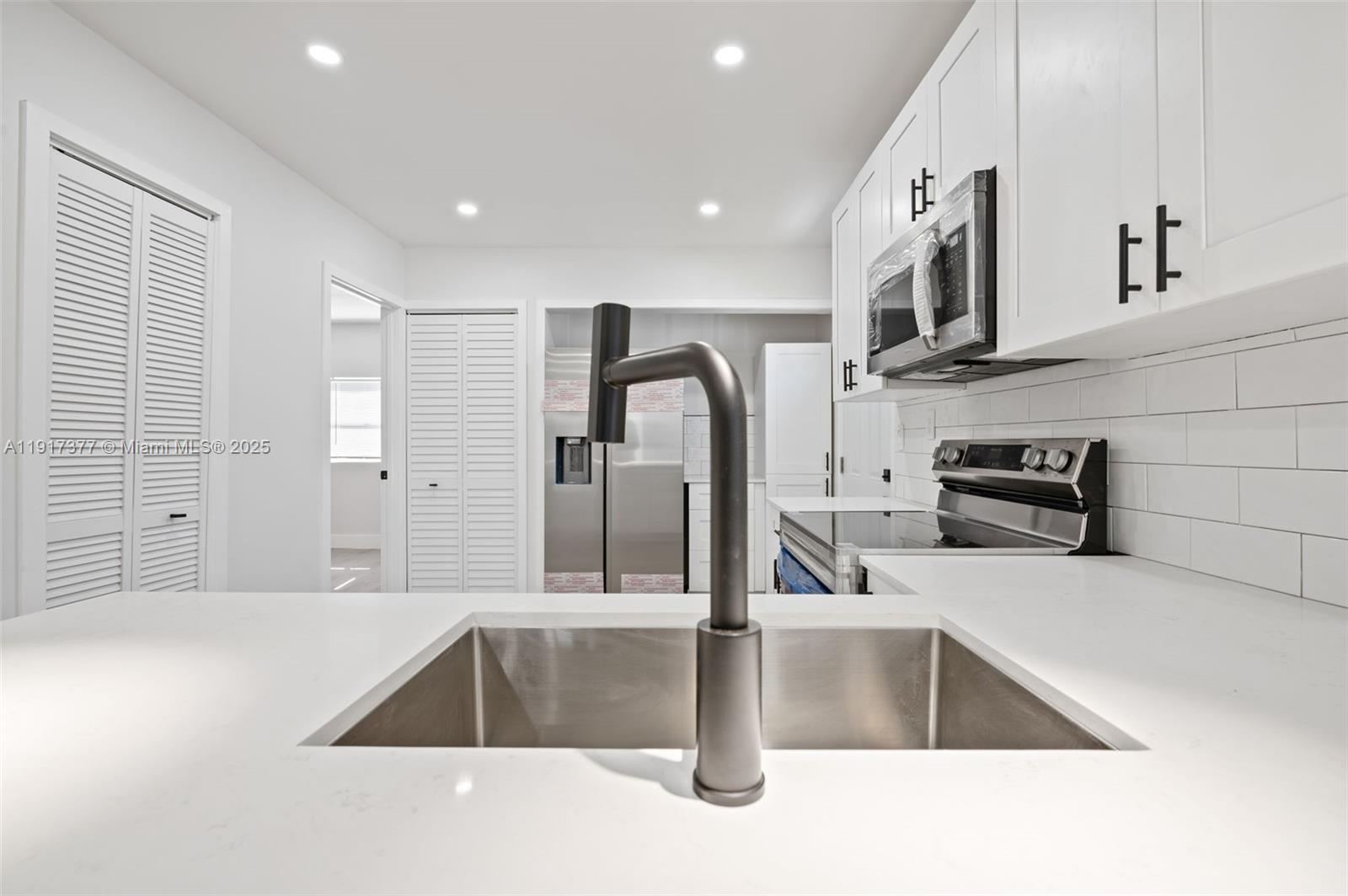 1844 Northwest 67th Street Miami, FL 33147 - Photo 14 of 27 a kitchen with stainless steel appliances granite countertop a sink and a stove top oven with wooden floor