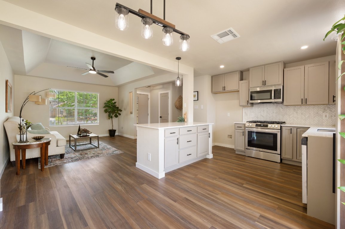a kitchen with stainless steel appliances kitchen island wooden floors and white cabinets