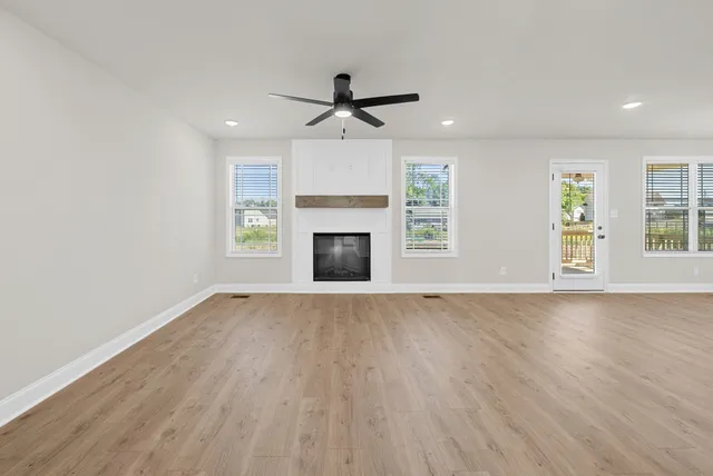 an empty room with windows and fireplace