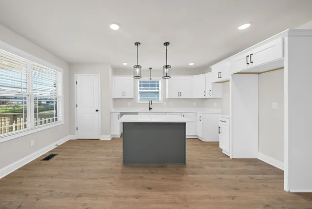 a large white kitchen with a sink dishwasher a stove and a refrigerator with wooden floor