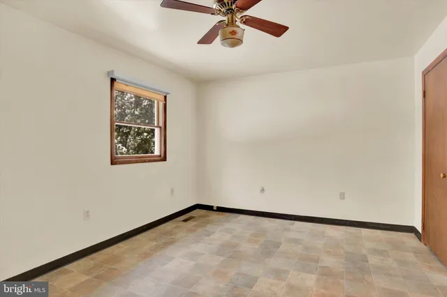 an empty room with a ceiling fan and window