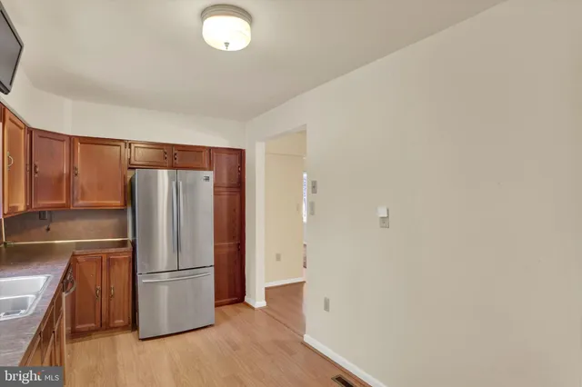 a view of a kitchen with a refrigerator a stove top oven and cabinets