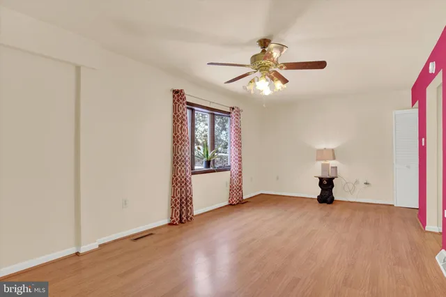 a view of empty room with wooden floor and fan
