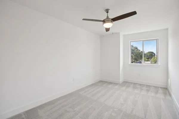 an empty room with a window and a ceiling fan