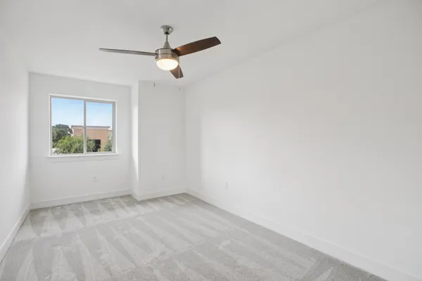 an empty room with a window and a ceiling fan