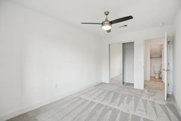 an empty room with closet and ceiling fan