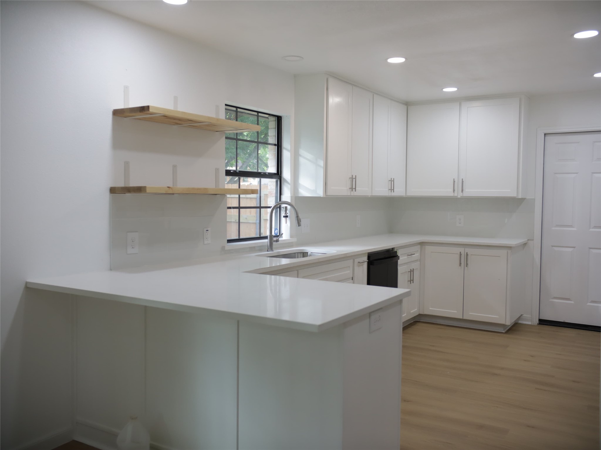 1612 Buttercup Road Pflugerville, TX 78660 - Photo 5 of 16 A well-lit kitchen with sleek white cabinetry and warm wood flooring.