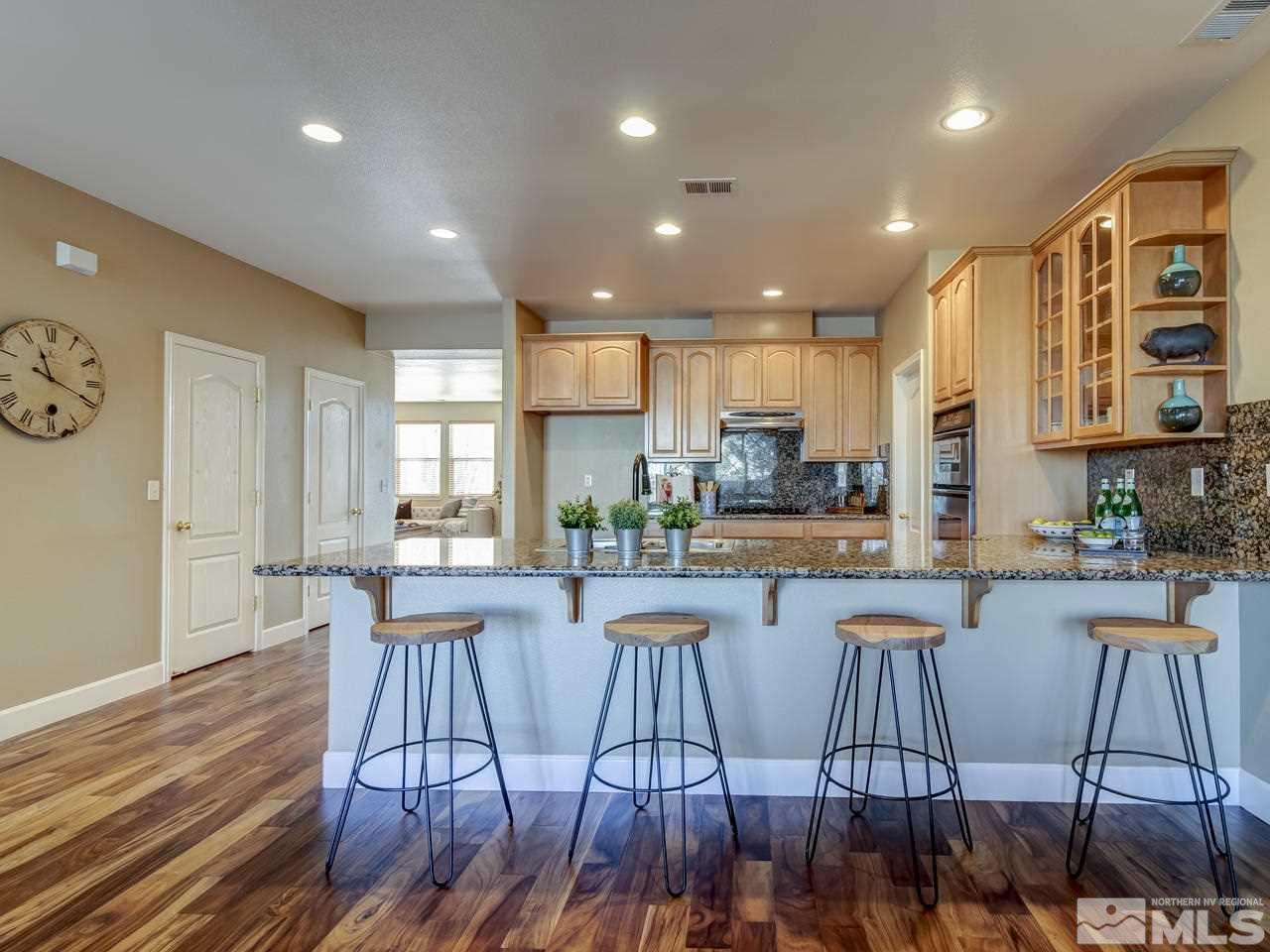 10803 Rushing Flume Drive Reno, NV 89521 - Photo 9 of 22 a kitchen with stainless steel appliances granite countertop a stove top oven a dining table and chairs with wooden floor