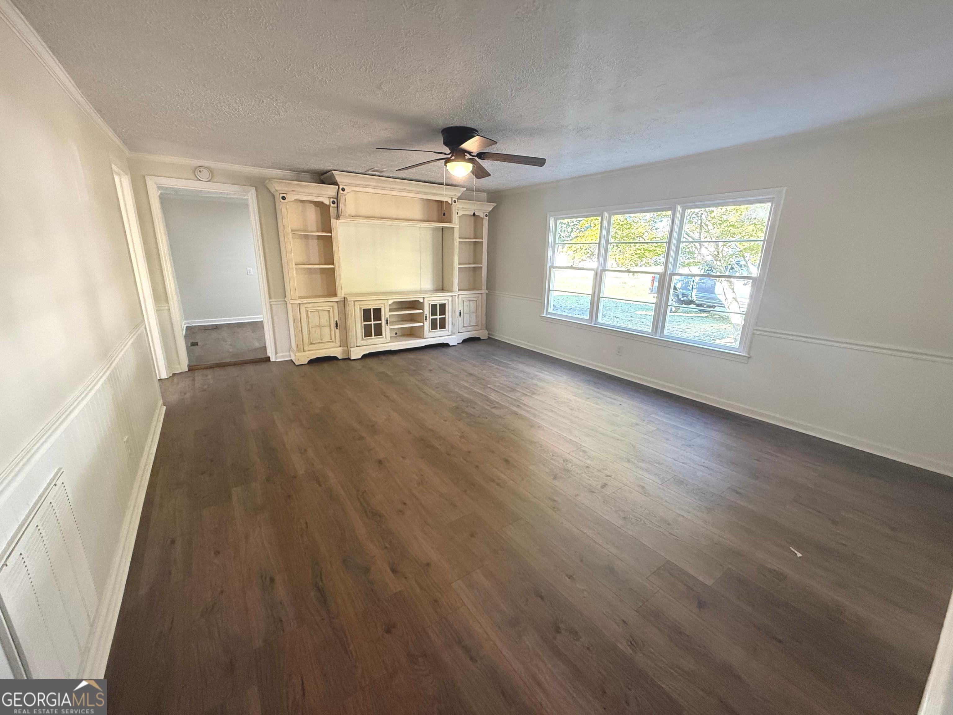 405 Monroe Street Garfield, GA 30425 - Photo 16 of 30 an empty room with wooden floor ceiling fan and windows