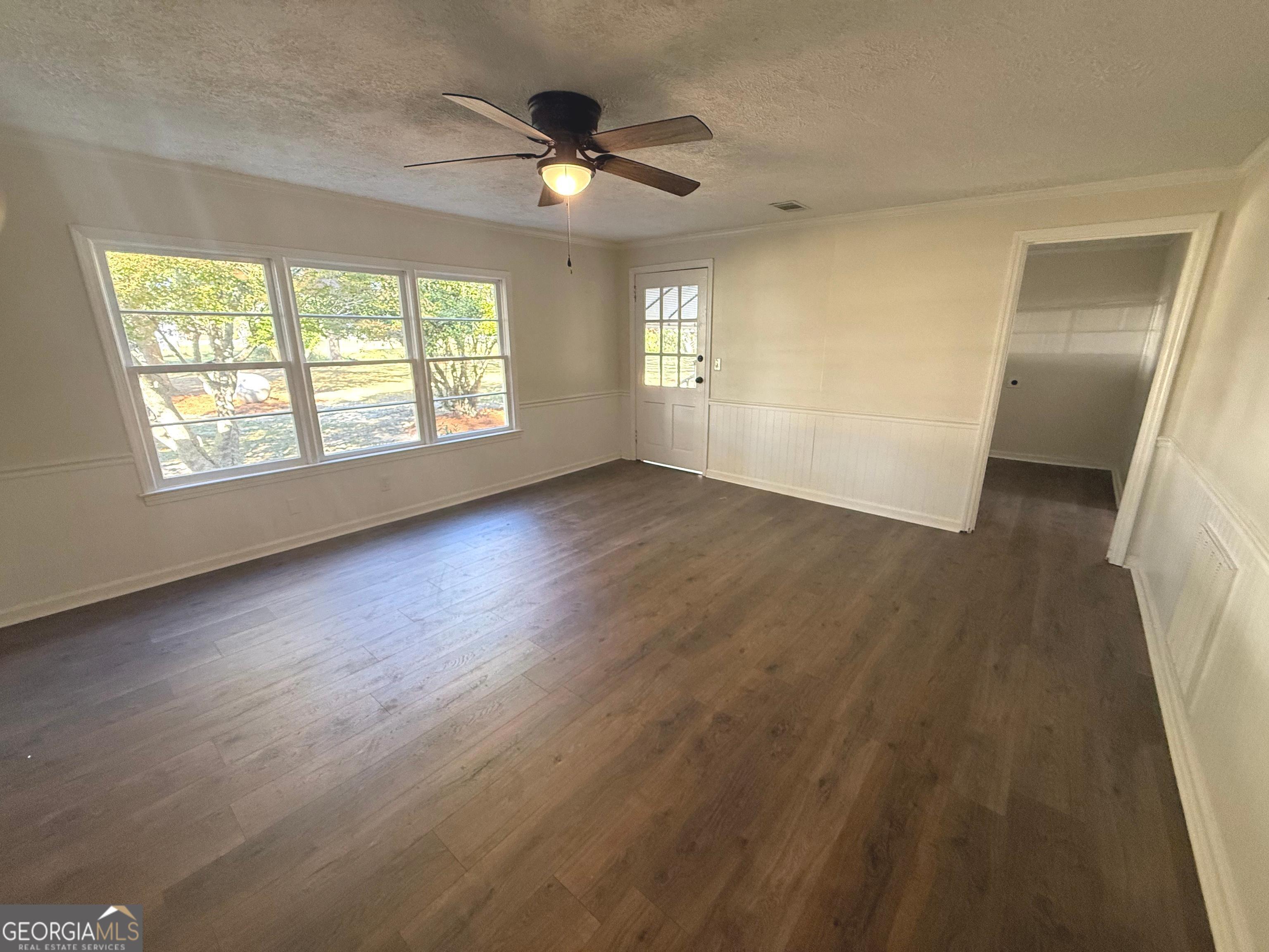 405 Monroe Street Garfield, GA 30425 - Photo 17 of 30 an empty room with wooden floor fan and windows