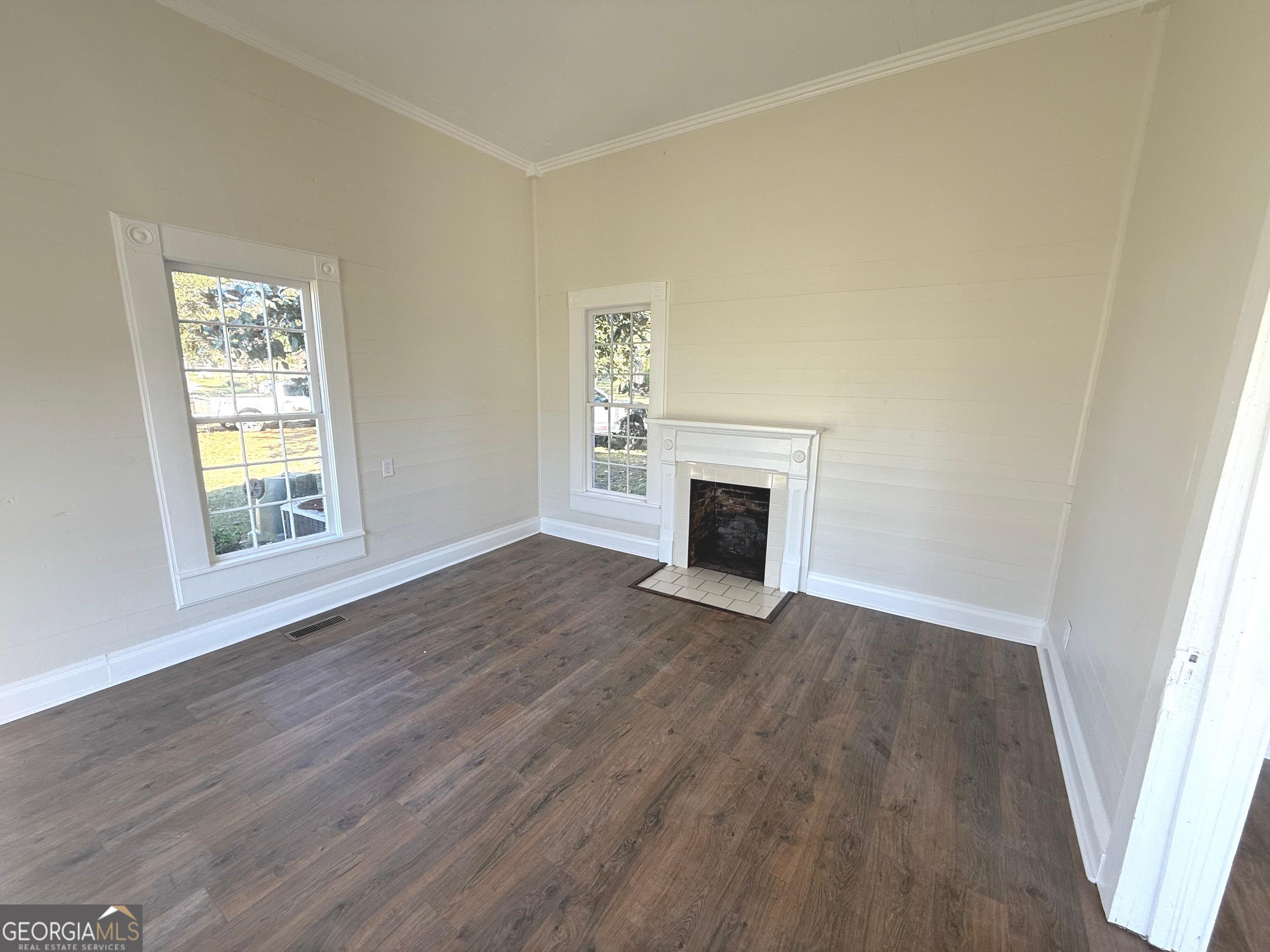 405 Monroe Street Garfield, GA 30425 - Photo 8 of 30 an empty room with wooden floor a fireplace and windows