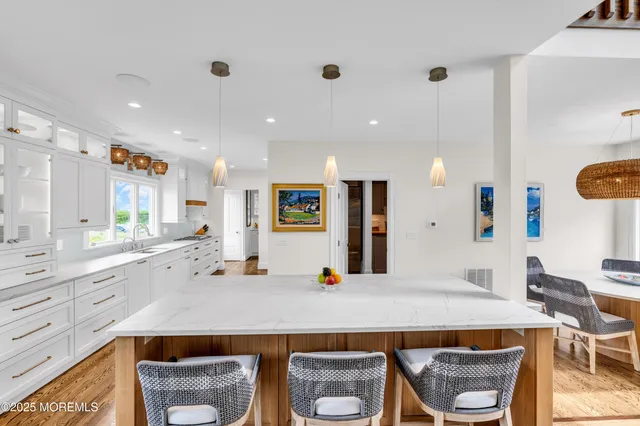 a large white kitchen with kitchen island white cabinets and stainless steel appliances