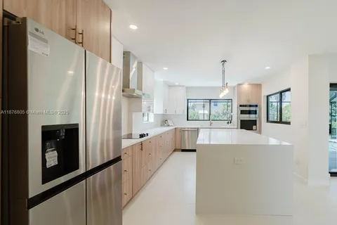 a large white kitchen with a large window and stainless steel appliances