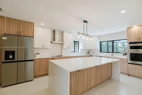 a large kitchen with stainless steel appliances a sink and a refrigerator