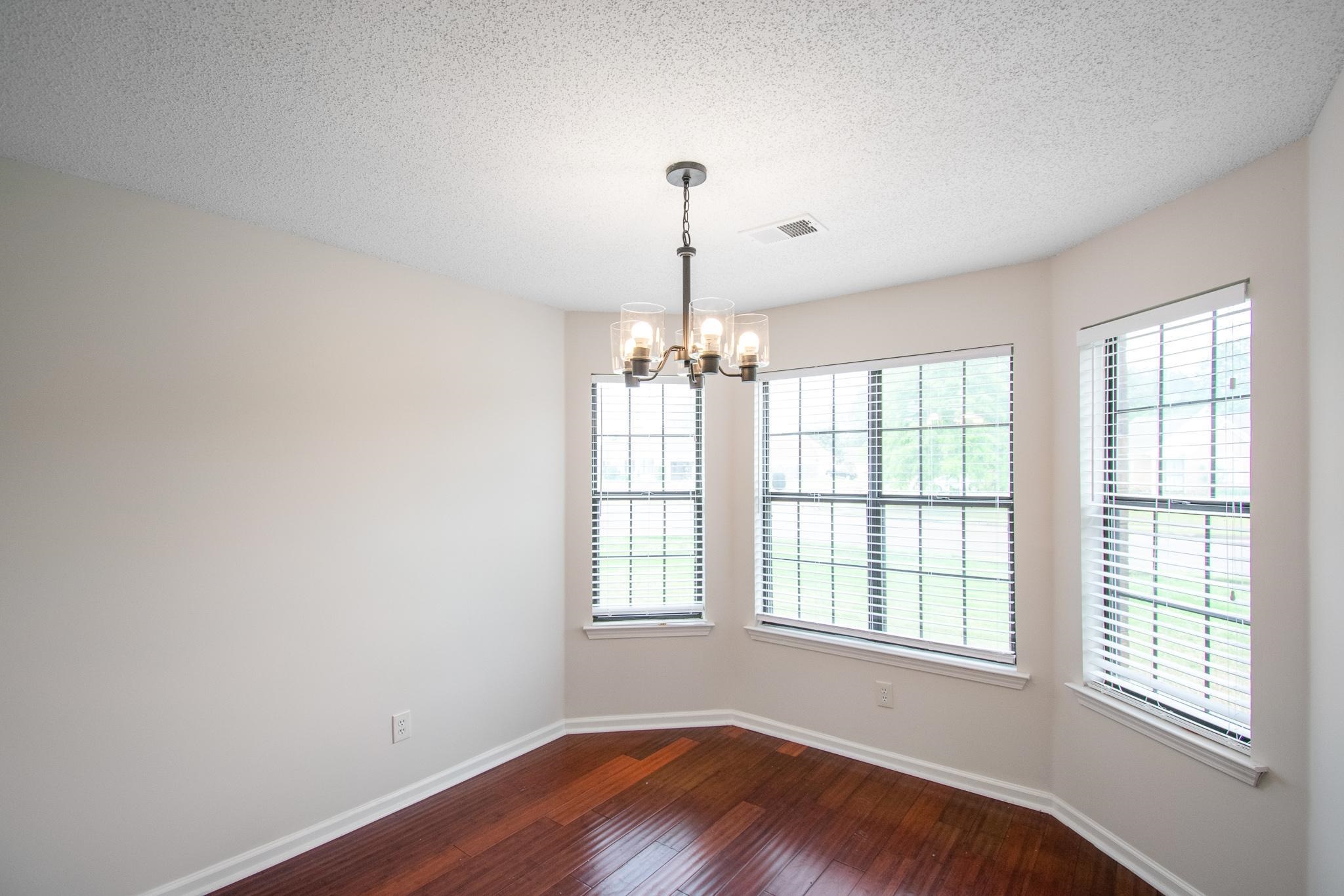 6909 Finch Road Memphis, TN 38141 - Photo 6 of 20 a view of an empty room with wooden floor and a window