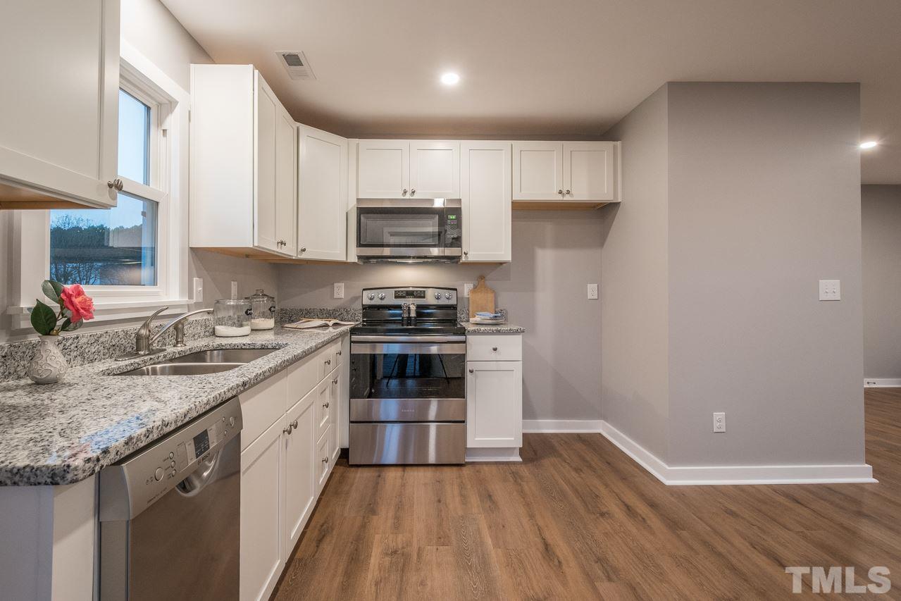 166 Hannah Creek Road Four Oaks, NC 27524 - Photo 6 of 20 a kitchen with kitchen island granite countertop a sink cabinets and stainless steel appliances