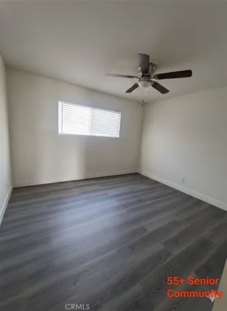 an empty room with wooden floor chandelier fan and windows