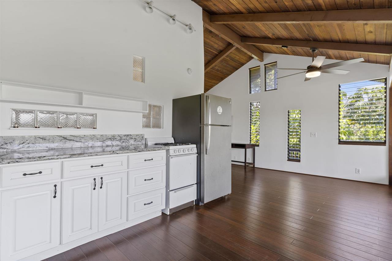 2560 Kokomo Road Haiku, HI 96708 - Photo 15 of 30 a kitchen with granite countertop white cabinets and wooden floor