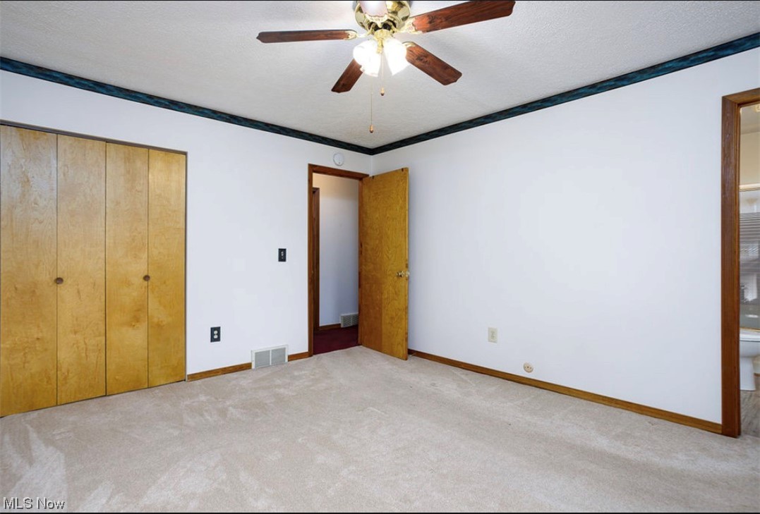 9066 Crow Road Litchfield, OH 44253 - Photo 22 of 28 Unfurnished bedroom with ceiling fan, a closet, ensuite bath, and light colored carpet