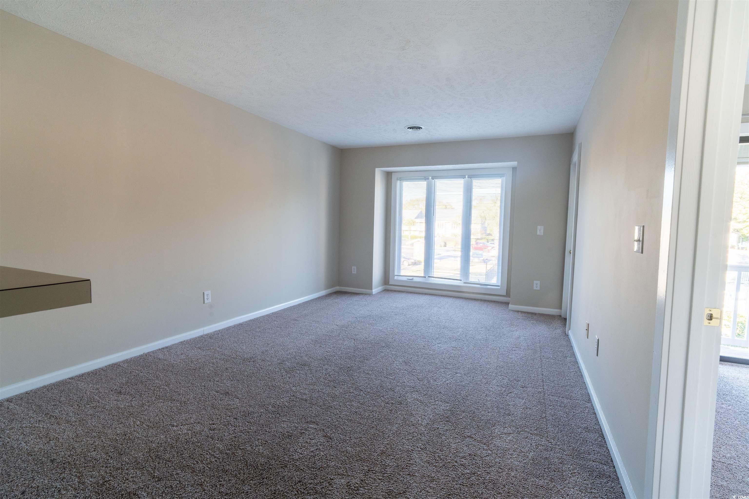 4708 Cobblestone Drive, Unit I8 Myrtle Beach, SC 29577 - Photo 7 of 15 Carpeted spare room featuring baseboards and a textured ceiling
