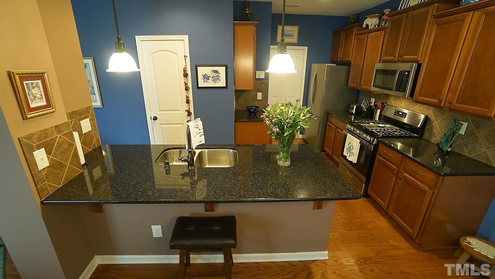 10115 Barnhart Way Raleigh, NC 27617 - Photo 19 of 60 a view of kitchen island with stainless steel appliances granite countertop sink stove and refrigerator